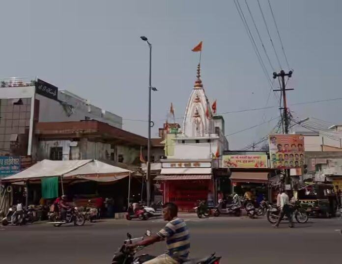मुख्य सड़क के किनारे स्थित बैरागढ़ काली माता मंदिर और उसके सामने व्यस्त ट्रैफिक और दोपहिया वाहन सवार।