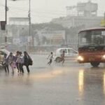 तेज बारिश के बीच भोपाल की सड़क पार करते स्कूली बच्चे और बस