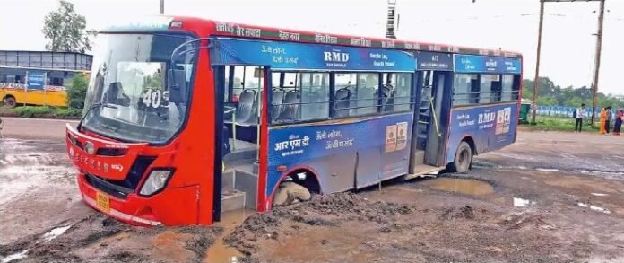 भोपाल पटेल नगर में धंसी सड़क के गड्ढे में फंसी नगर निगम की बस — सड़क की जर्जर हालत और PWD की लापरवाही का उदाहरण।