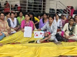 भोपाल में धरना दे रही ANM महिला कार्यकर्ता, एक महिला लेटी हुई है और हाथ में खून से लिखा पत्र पकड़े हुए हैं।