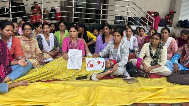 भोपाल में धरना दे रही ANM महिला कार्यकर्ता, एक महिला लेटी हुई है और हाथ में खून से लिखा पत्र पकड़े हुए हैं।